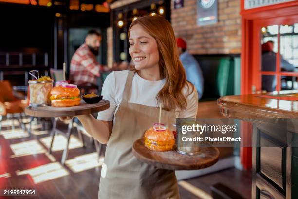 bustling pub scene with a smiling server - empregada de mesa imagens e fotografias de stock