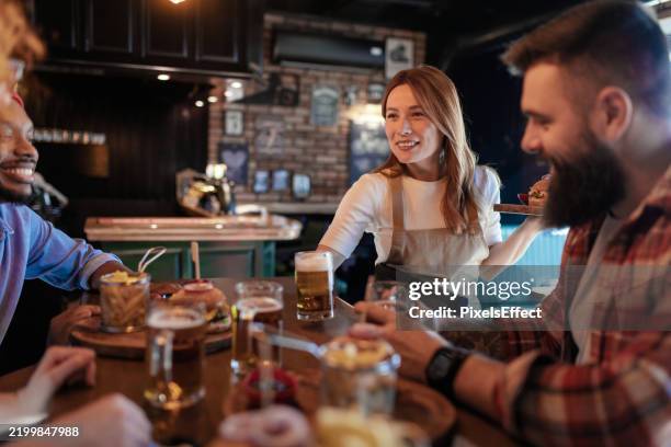 friendly waitress enhances the dining experience at a rustic pub - waitress stock pictures, royalty-free photos & images