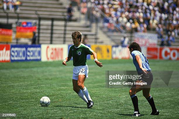 Pierre Littbarski of West Germany looks to take the ball past Sergio Santin of Uruguay during the FIFA World Cup Finals 1986 Group E match between...