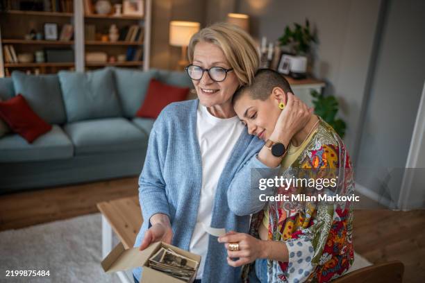 mother and daughter sharing a moment looking at old photos - looking at old photo stock pictures, royalty-free photos & images