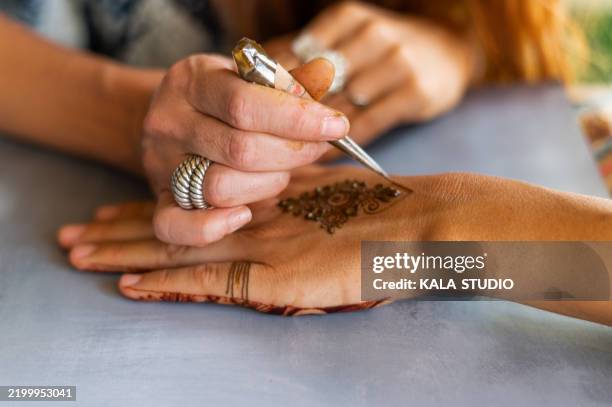 artist carefully applying henna tattoo on woman's hand - tatuagem de henna imagens e fotografias de stock