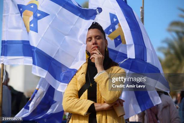 Woman stands among Israeli flags in hostages square prior the handover of four bodies taken by Hamas fighters on February 20, 2025 in Tel Aviv,...