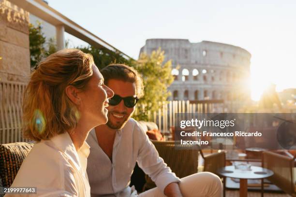 couple enjoys sunset views of the colosseum. romance, travel. - flitterwochen stock-fotos und bilder