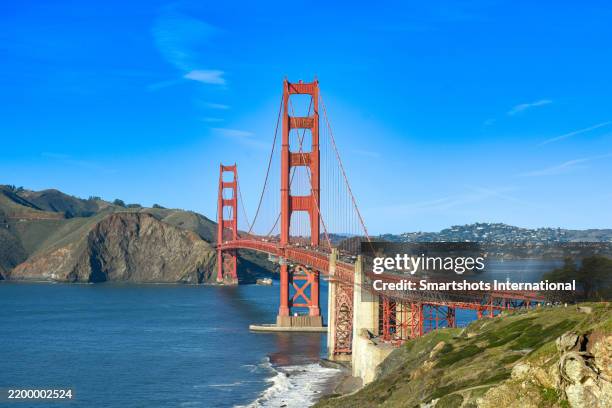 golden grate bridge with perfect blue sky and pacific ocean waves on san francisco bay in san francisco, california, usa - bucht-von-san-francisco stock-fotos und bilder