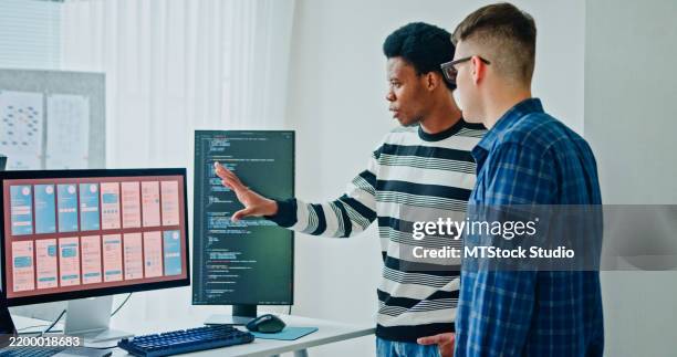 two male software developers meeting on multiple computer screens displaying programming code, collaborating on project standing in office. artificial intelligence and programming. - computer bug stock pictures, royalty-free photos & images