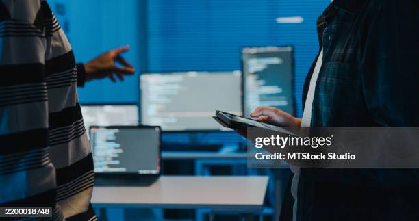 closeup group of it professionals collaborating on network security and data analysis using tablet and laptop in office at night. software developer, artificial intelligence and programming. - software development team stock pictures, royalty-free photos & images