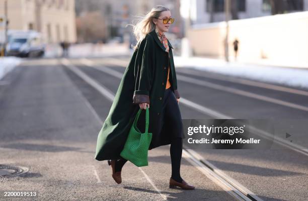 Lil Paulin seen wearing brown aviator sunglasses with orange lenses, orange / colorful flower pattern scarf, orange wool pullover, Wellington of...