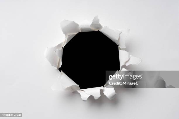 circular bullet hole in multi-layered white paper - bullet hole stock pictures, royalty-free photos & images