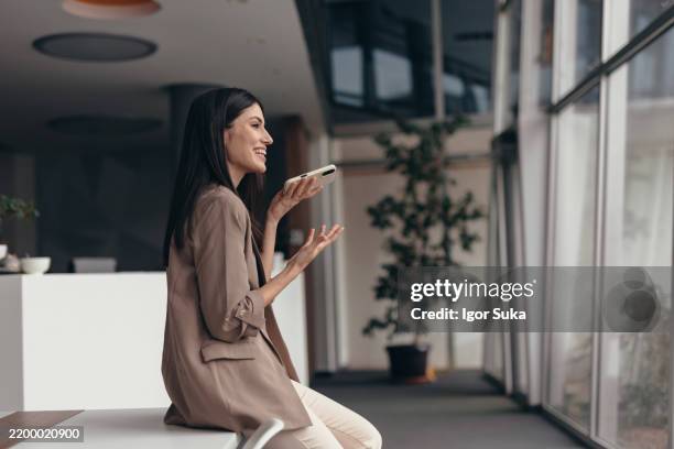 young businesswoman talking on speakerphone in modern office - conference phone stock pictures, royalty-free photos & images