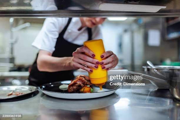 chef adding sauce to a gourmet dish in a restaurant kitchen - sauce stock pictures, royalty-free photos & images