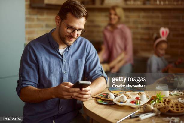 smiling man using mobile phone on easter in dining room. - easter breakfast stock pictures, royalty-free photos & images