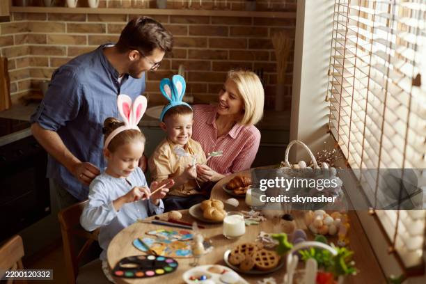 happy family feeling creative on easter in dining room. - easter breakfast stock pictures, royalty-free photos & images