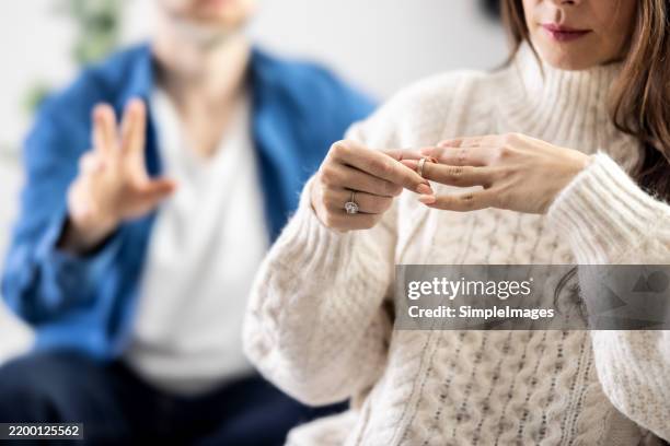 upset depressed young woman holding wedding ring indoors, breaking off engagement, ending relationship, abandoned wife, cheated bride making hard decision, broken heart, breakup and divorce concept - divorce photos et images de collection