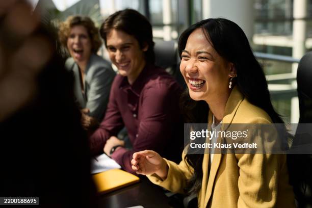 businesswoman laughing while sitting with colleagues - workplace wellbeing stock pictures, royalty-free photos & images