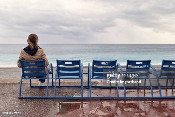 young woman looking at the sea in nice, alpes-maritimes, france. - off season stock pictures, royalty-free photos & images