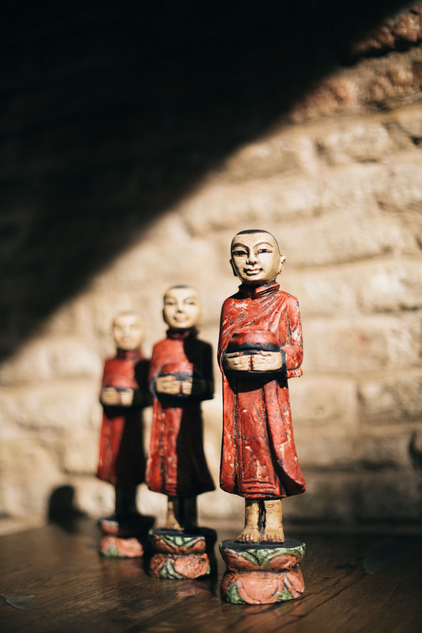 Traditional Thai monk statues holding alms bowls, Displayed against a rustic brick wall with warm sunlight, Cultural and spiritual decor for Thai restaurant ambiance and interior design Traditional Thai monk statues holding alms bowls, Displayed against a rustic brick wall with warm sunlight, Cultural and spiritual decor for Thai restaurant ambiance and interior design