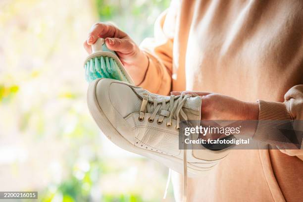 femme méconnaissable brossant des baskets blanches - chaussure en toile photos et images de collection