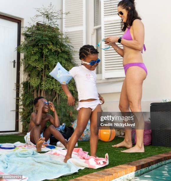 woman in swimwear with children by backyard swimming pool - arm band stock pictures, royalty-free photos & images