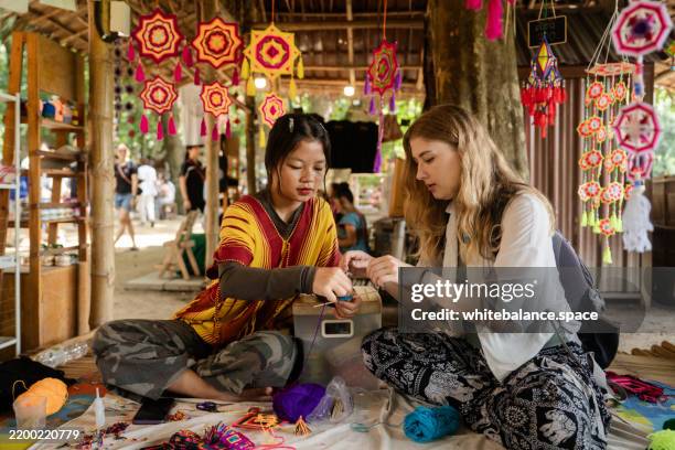 una turista straniera che fa artigianato durante un laboratorio con la gente del posto - turismo esperienziale foto e immagini stock