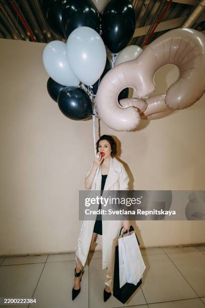 stylish woman holding shopping bags and balloons celebrating 60th birthday - happy 60th birthday photos et images de collection