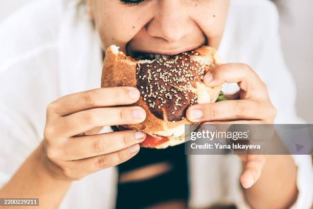 young woman enjoying a delicious sesame burger with intense flavor - ready to eat stock pictures, royalty-free photos & images