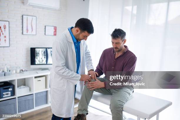 arzt bei der kontrolle des kniegelenks eines männlichen patienten in der orthopädischen klinik - orthopädie stock-fotos und bilder