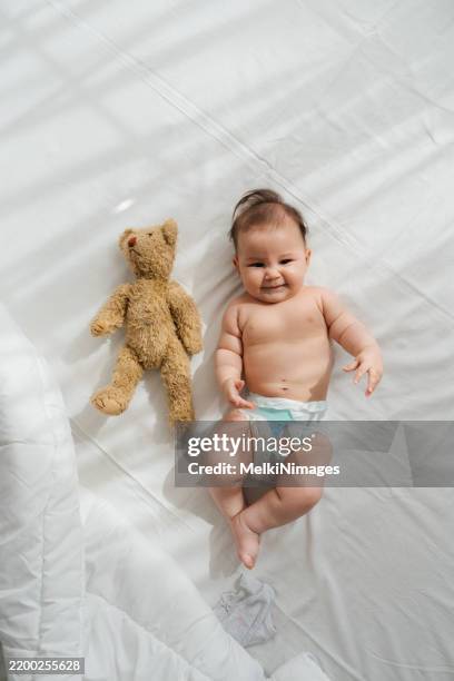 sunny smiles and teddy bear hugs - baby diaper sleeping stock pictures, royalty-free photos & images