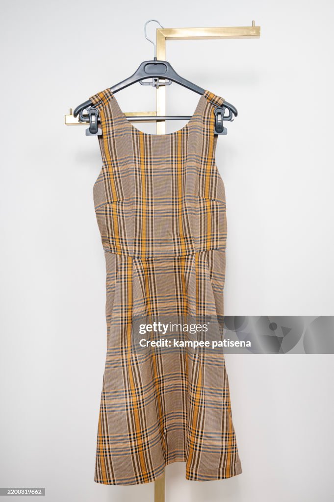 A dress with a plaid pattern is hanging on a hanger