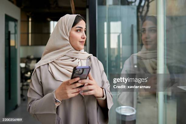 contemplative saudi woman looking through office window - saudi arabia woman stock pictures, royalty-free photos & images