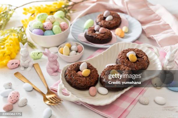 baked chocolate donuts with chocolate shavings and easter chocolate eggs - easter breakfast stock pictures, royalty-free photos & images