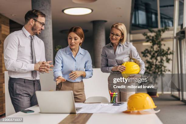 architetti che discutono di un progetto su un laptop in ufficio - designer industriale foto e immagini stock