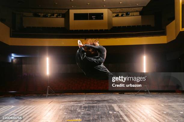 giovane donna che esegue una danza interpretativa in un teatro vuoto - danza moderna foto e immagini stock