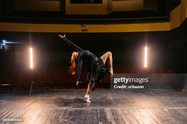 junge frau, die interpretativen tanz in einem leeren theater aufführt - swing tanz stock-fotos und bilder