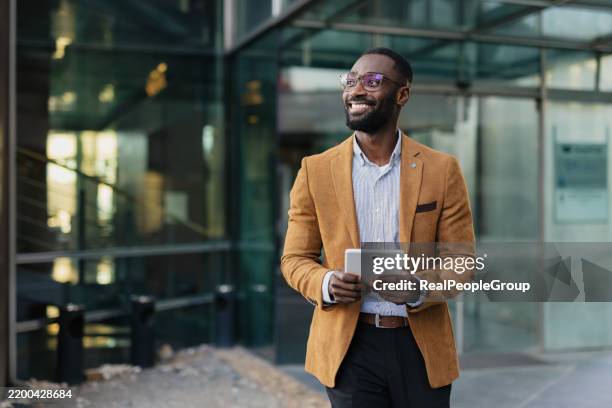 selbstbewusster geschäftsmann mit tablet in urbaner umgebung - business people stock-fotos und bilder