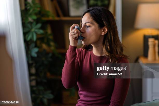 jeune femme utilisant son inhalateur pour l’asthme à la maison - allergie photos et images de collection