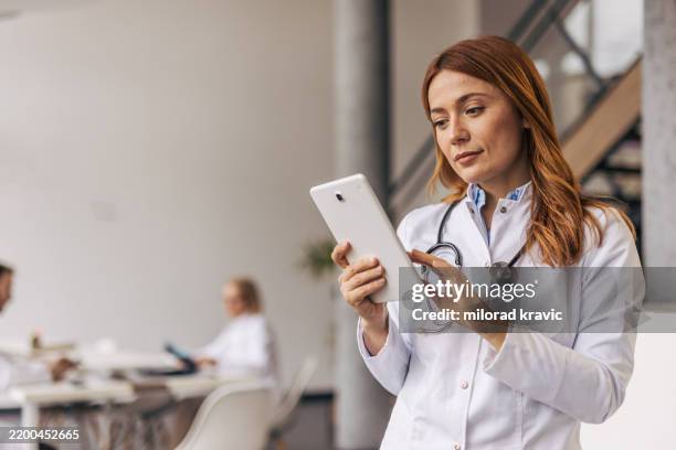 ärztin mit digitalem tablet in modernem krankenhaus - krankenakte stock-fotos und bilder