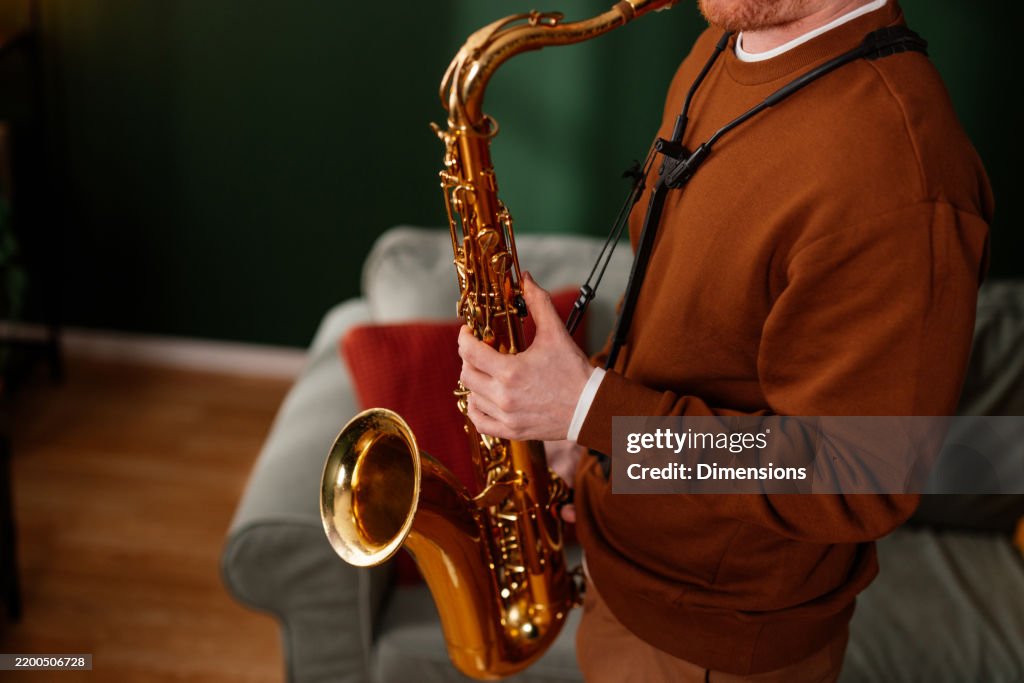 Musician playing saxophone at home during leisure time