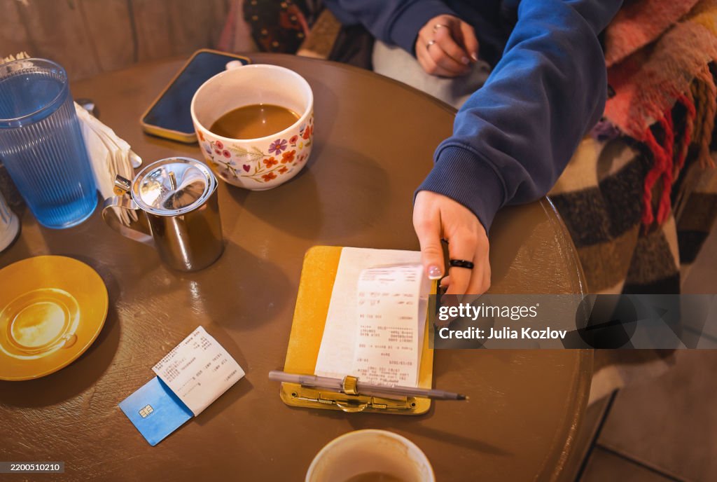 Breakfast in café-shop. 24-year-old woman is about to sign the check.