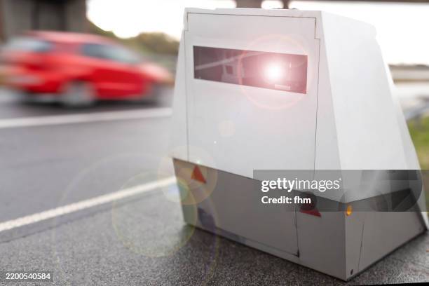 triggering speed camera of the police with a too fast passing red car - lasergun stockfoto's en -beelden