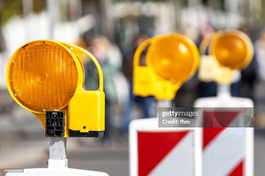 Three yellow warning lights at a construction site on the street
