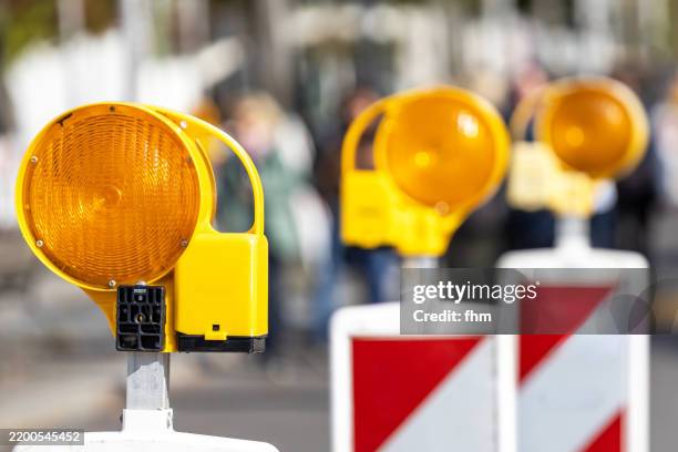 three yellow warning lights at a construction site on the street - wegenbouw stockfoto's en -beelden