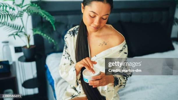 mujer en casa usando crema corporal de manteca de karité - crema corporal fotografías e imágenes de stock
