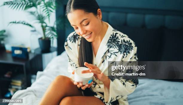 woman at home using shea butter body cream - shea butter stock pictures, royalty-free photos & images