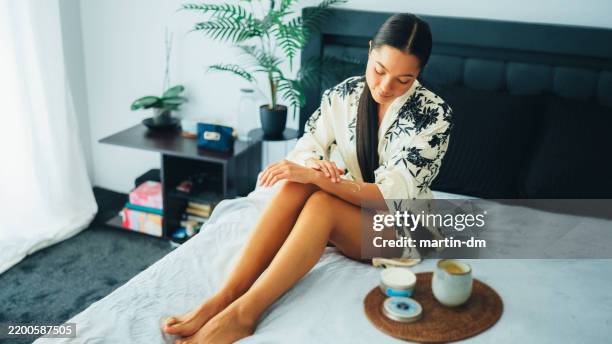 woman at home using shea butter body cream - shea butter stock pictures, royalty-free photos & images