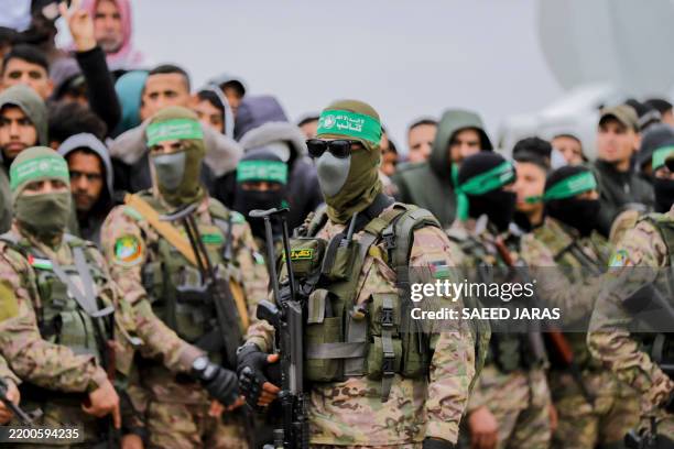 Hamas fighters gather at the site of the handing over of Israeli hostages at the Nuseirat refugee camp in the central Gaza Strip as part of the...