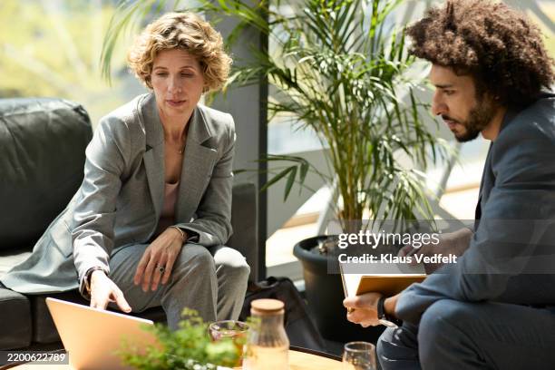 businesswoman showing stats to male colleague - formele zakelijke kleding stockfoto's en -beelden