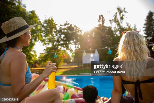 amigos ver cine al aire libre desde la piscina - flotar sobre agua fotografías e imágenes de stock