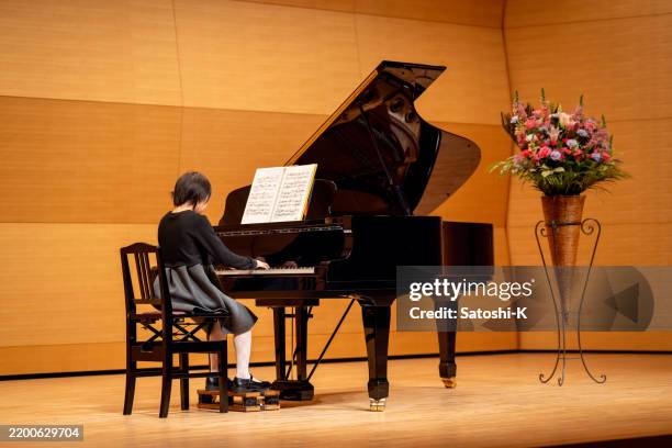 teenager-mädchen, das klavier im konzertsaal spielt - konzertflügel stock-fotos und bilder