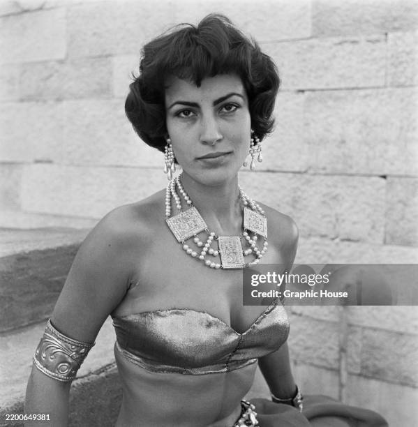 Greek actress and singer Irene Papas, wearing a strapless outfit with an arm ring, elaborate drop earrings, and necklace, 20th October 1953.