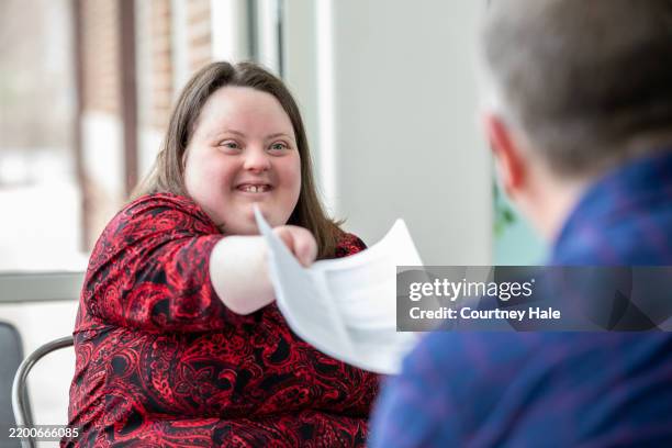 a young woman with down syndrome shares a copy of her resume with a potential employer. - advocacy stock pictures, royalty-free photos & images